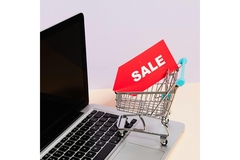 Image A mini shopping cart with a sale sign on it on top of a laptop.