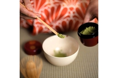 Image adding matcha to bowl next to matcha whisk