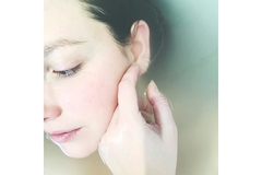 Image A woman touching her face while in water.