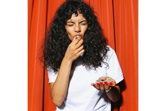 Image woman in white shirt eating candies.
