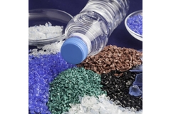 Image Plastic resins in different colors next to plastic-based water bottle.