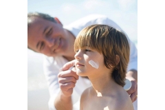 father applies sunscreen on child's face