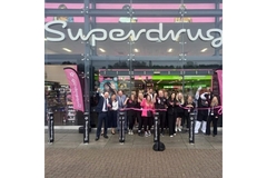 Superdrug store from the outside with people lined up in the front.