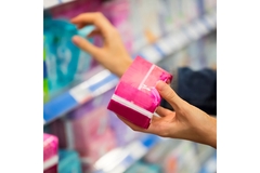 Image A hand reaching for period products on the shelf at a store.