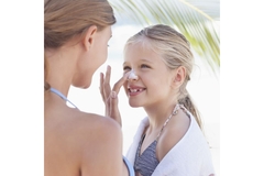 Image mom applies sunscreen on daughter's nose
