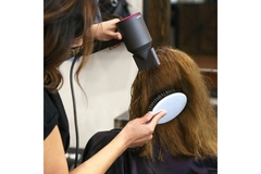 Image A hair stylist using a Dyson hair dryer on a clients hair.