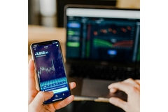 Image A hand holding a phone with the stock market on it.