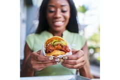 a girl holding fried chicken burger.
