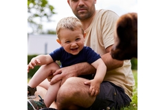 Image A man holding a child who is laughing.