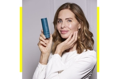Woman smiling holding Trinny London product by cheek