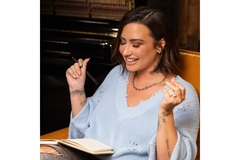 demi lavato sitting on chair smiling and snapping fingers