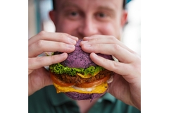 Image man eating a vegan colorful burger.