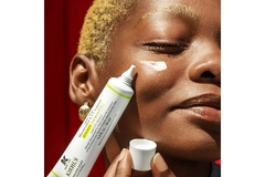 Image A woman applying Khiel's product to her cheek and smiling.