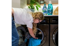 Image A woman reaching into the washing machine.