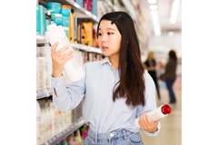 Woman buying hair care products in shop by product asile