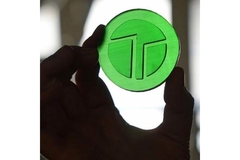 A hand holding a green piece of AggiePol.