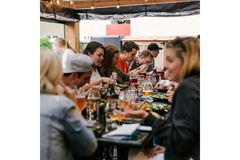 A group of people eating food at a long table in a resteraunt.