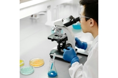 Image Researcher examining stool samples in a lab under a microscope