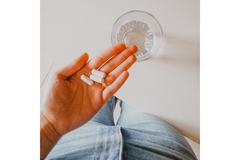 Image A woman holds some pills in her hands.