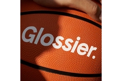 Image A hand on a basketball with Glossier on it.