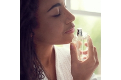 Image A woman smelling a perfume bottle.
