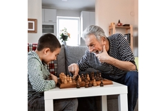 A man plays chess against a child and laughs at him.