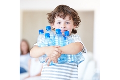 Image A little boy is holding a stack of water bottles.