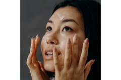 Image A woman with cream on her face about to touch it.