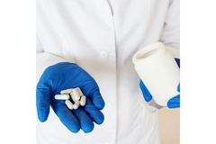 Image Person in a lab coat holding out a hand filled with supplements.