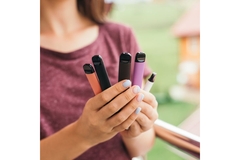 Image Woman holding different vapes in hand.