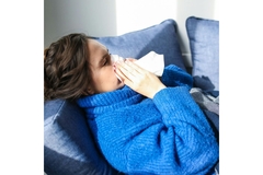 Image Woman suffering from COVID blowing her nose.