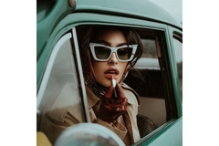 woman applies lipstick looking outside a car window