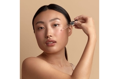 Image woman applying product to cheek using dropper