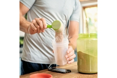 Man scooping lactoferrin protein in a bottle to make a shake.