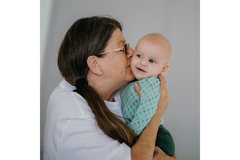 Image An older woman kissed a baby on the cheek.