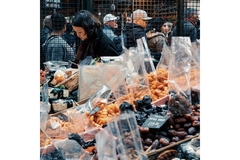 Image A person standing in front of a market filled with plastic-packaged food products