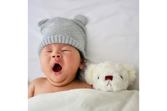 Image A cute baby yawning on a bed.