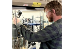 Image A person wearing goggles and working on a machine.