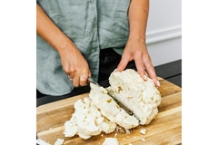 Person cutting up a cauliflower.
