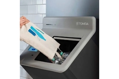 A hand putting a bag of bottles into a reverse vending machine.