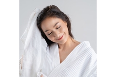 Image Smiling woman in bathrobe rubs towel on her hair