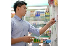 Image A man pulling a bottle of pill off a grocery store shelf.
