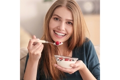 Image a woman eating yogurt.