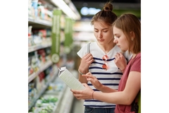 Image two women reading food labels on a tetrapak container in a supermarket.