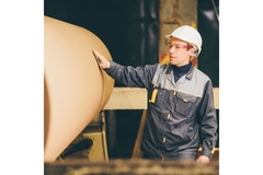 Image Rolled up paper with worker standing next to it.