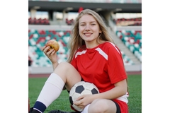 Image Young female footballer eating an apple