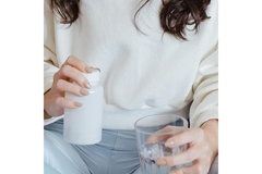 A hand holding a vitamin container.