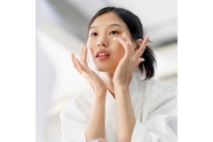 Image A girl applying eye cream on in the mirror.