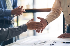 Image Two men shaking hands over a big business deal.