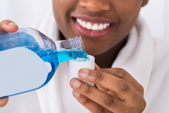 Image close up of a woman pouring mouthwash in lid